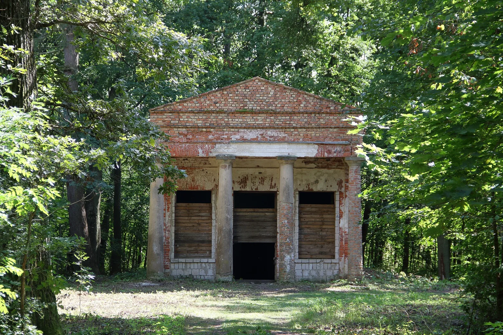 Alte Eichen und verfallene Pavillons prägen das Bild der Allee im Park von Park von Schloss Sztynort im Sommer 2019.